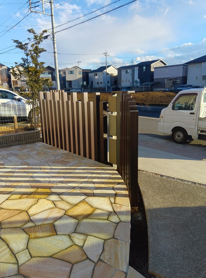 上尾市の外構施工事例｜列柱が道路側から庭へL字に立ち上がる様子と乱形石テラスが確認でき