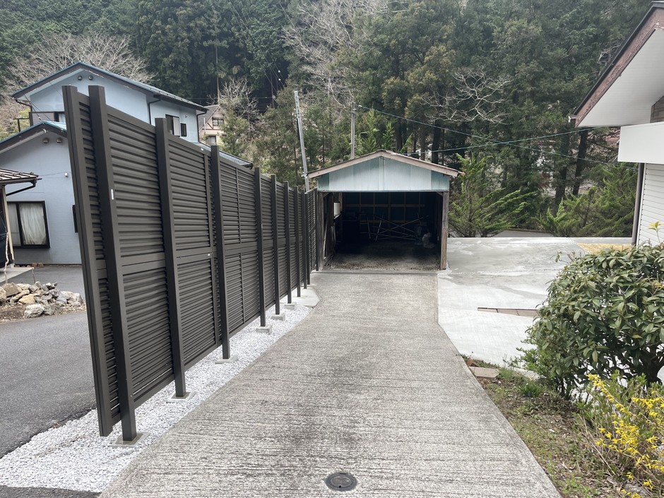 狭山市の外構施工事例｜フェンス列と土間コンクリートのアプローチが奥の既存車庫まで伸びる全景