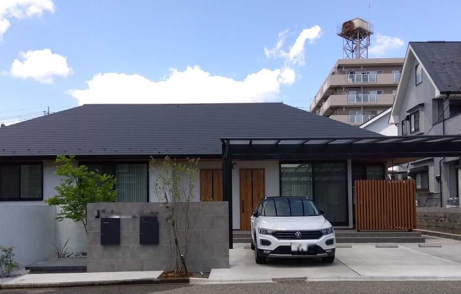 埼玉県川越市の施工事例｜道路から見た正面全景。塗り壁とタイル貼りの門柱、片流れカーポート、白い土間