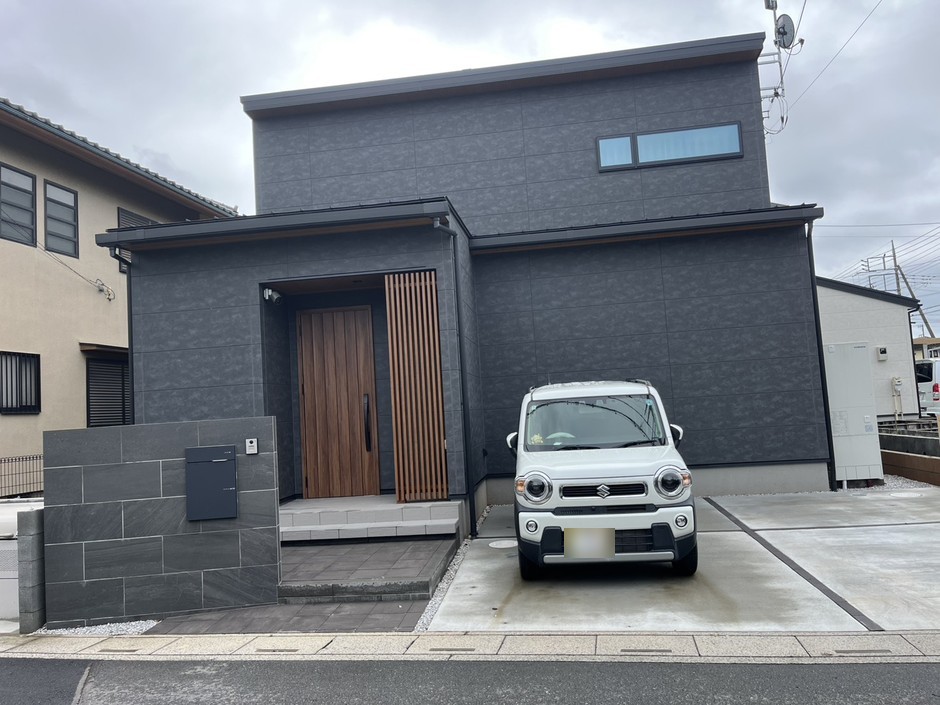 埼玉県坂戸市の施工事例｜道路正面からの全景で、黒い大判タイルの門袖・ポスト・玄関前のステップ・土間コンクリートと建